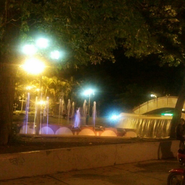 a motorcycle sits by a fountain at night