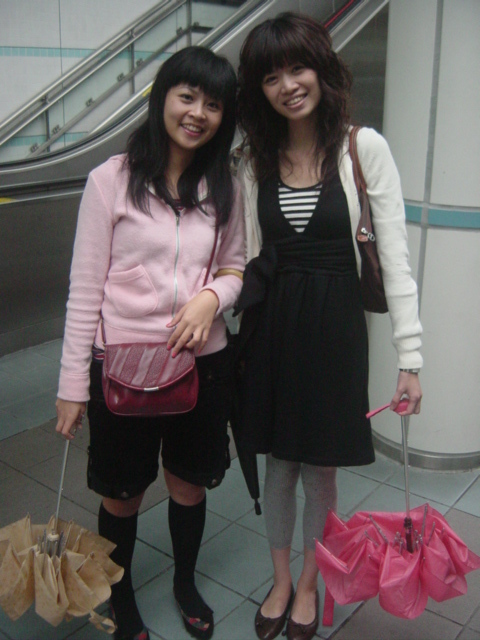 two women posing for a picture, one carrying a pink purse