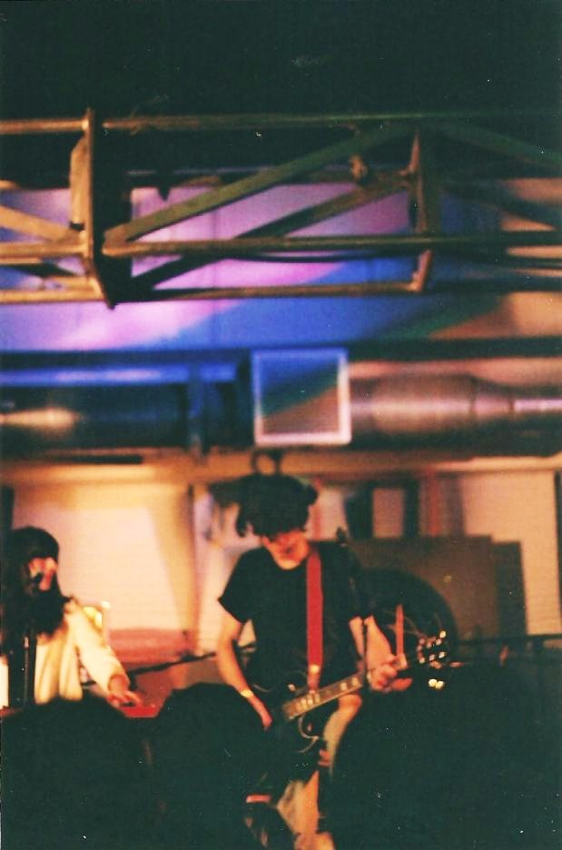 two people with guitar and drums playing in a room