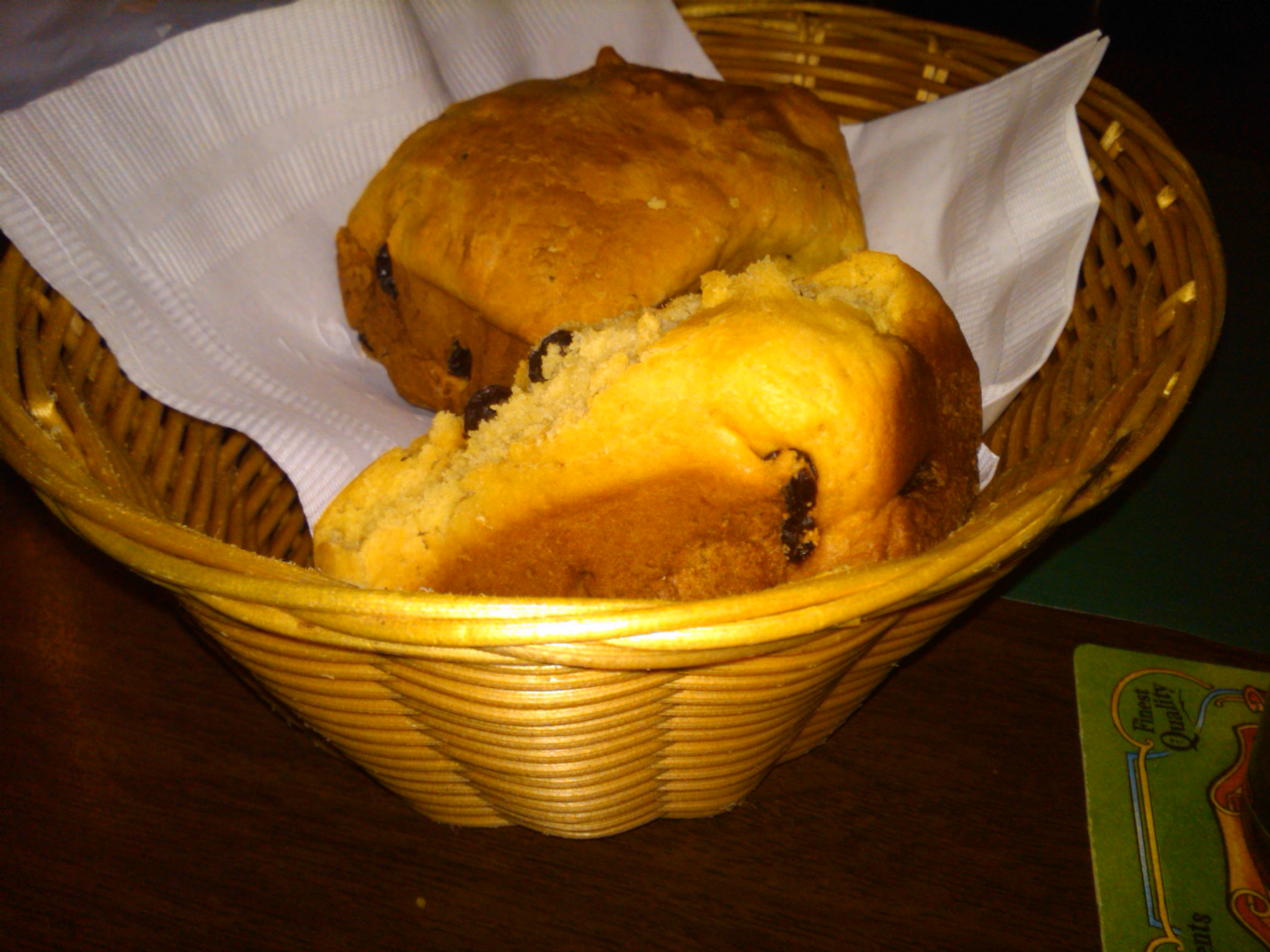 a basket with muffins, rolls, and napkins