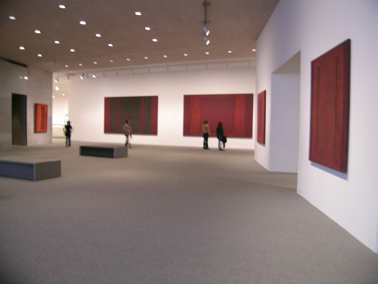 three people in an art gallery viewing paintings on canvas