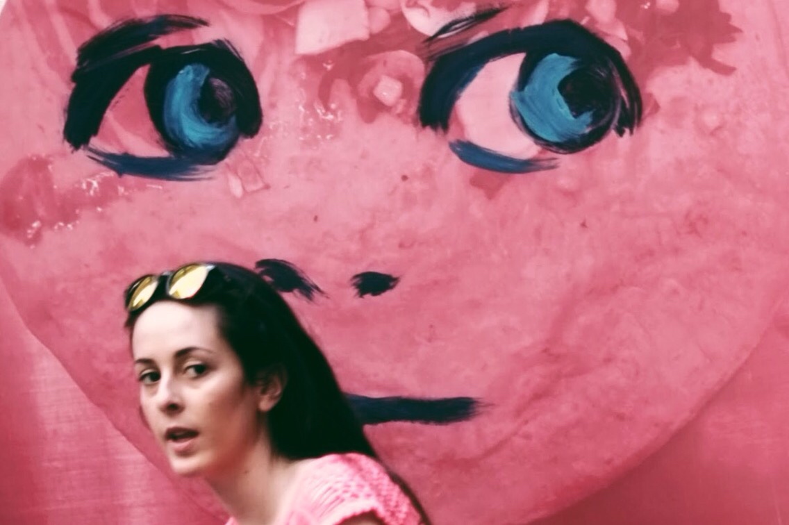 there is a woman standing in front of a large pink face