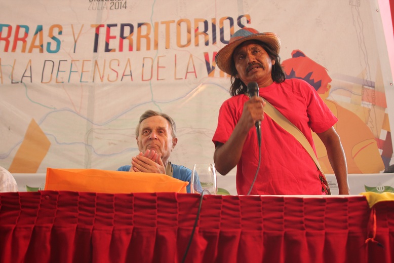 a man holding up a microphone and standing next to a man wearing a red shirt