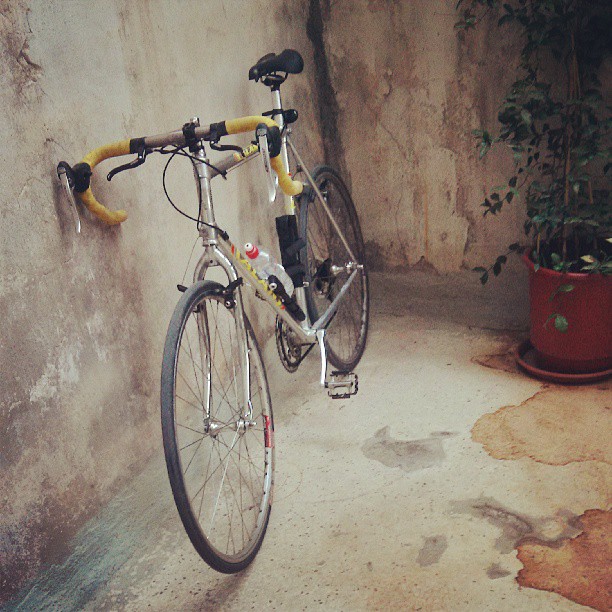 a white bike is parked next to a wall