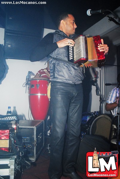 a man is playing an accordion with another man on the side