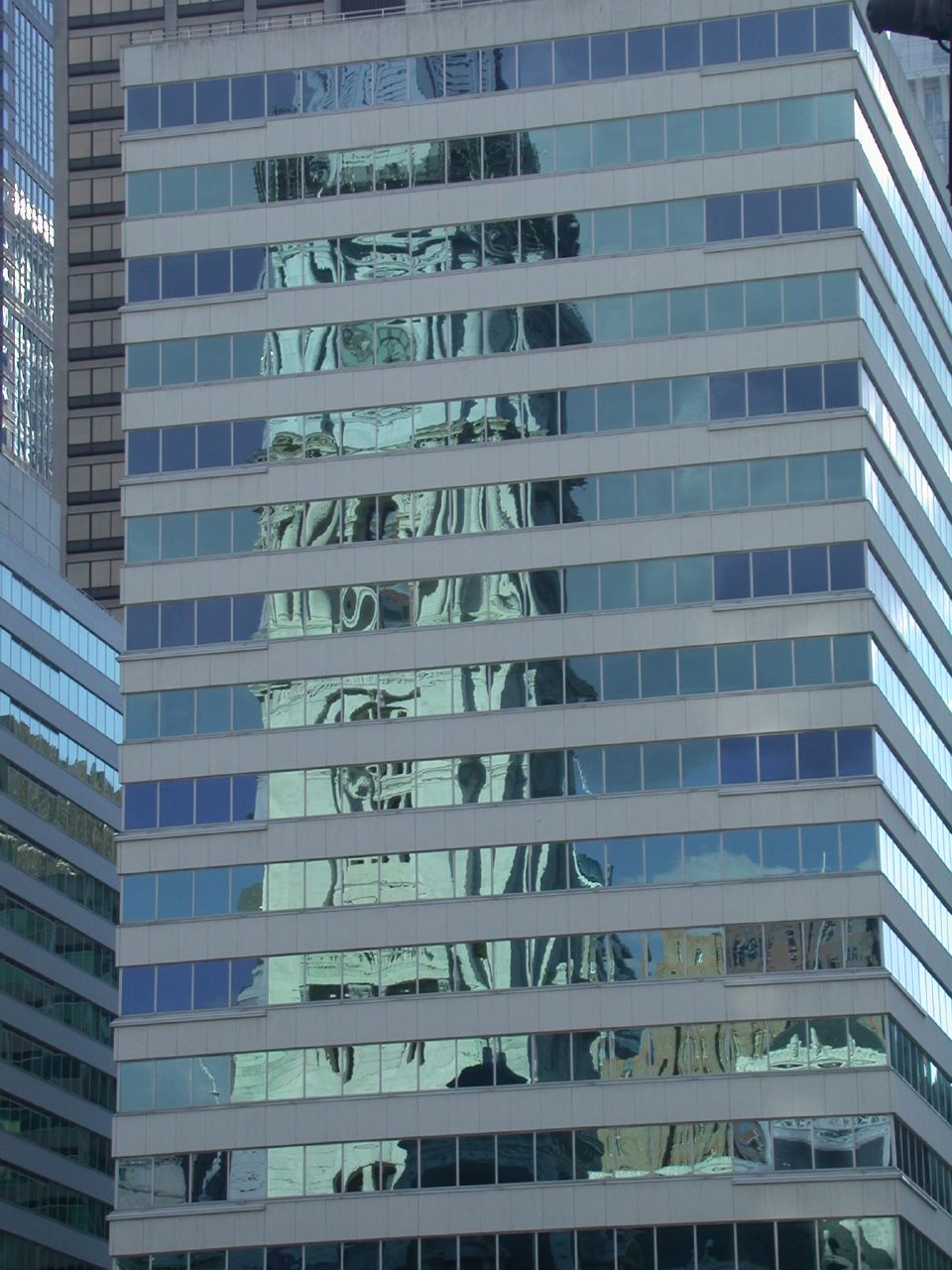 the side of a building has many windows and reflects in the glass