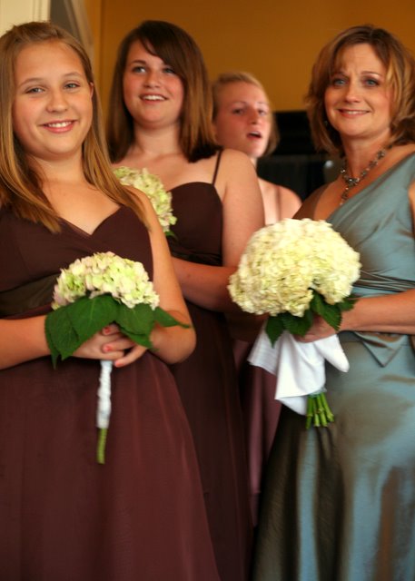 a group of people standing next to each other holding white and green flowers