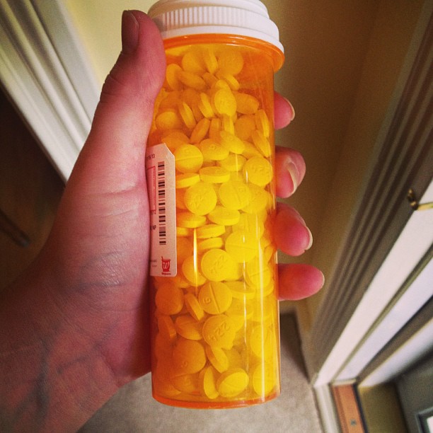 a hand holding a container full of pill pill