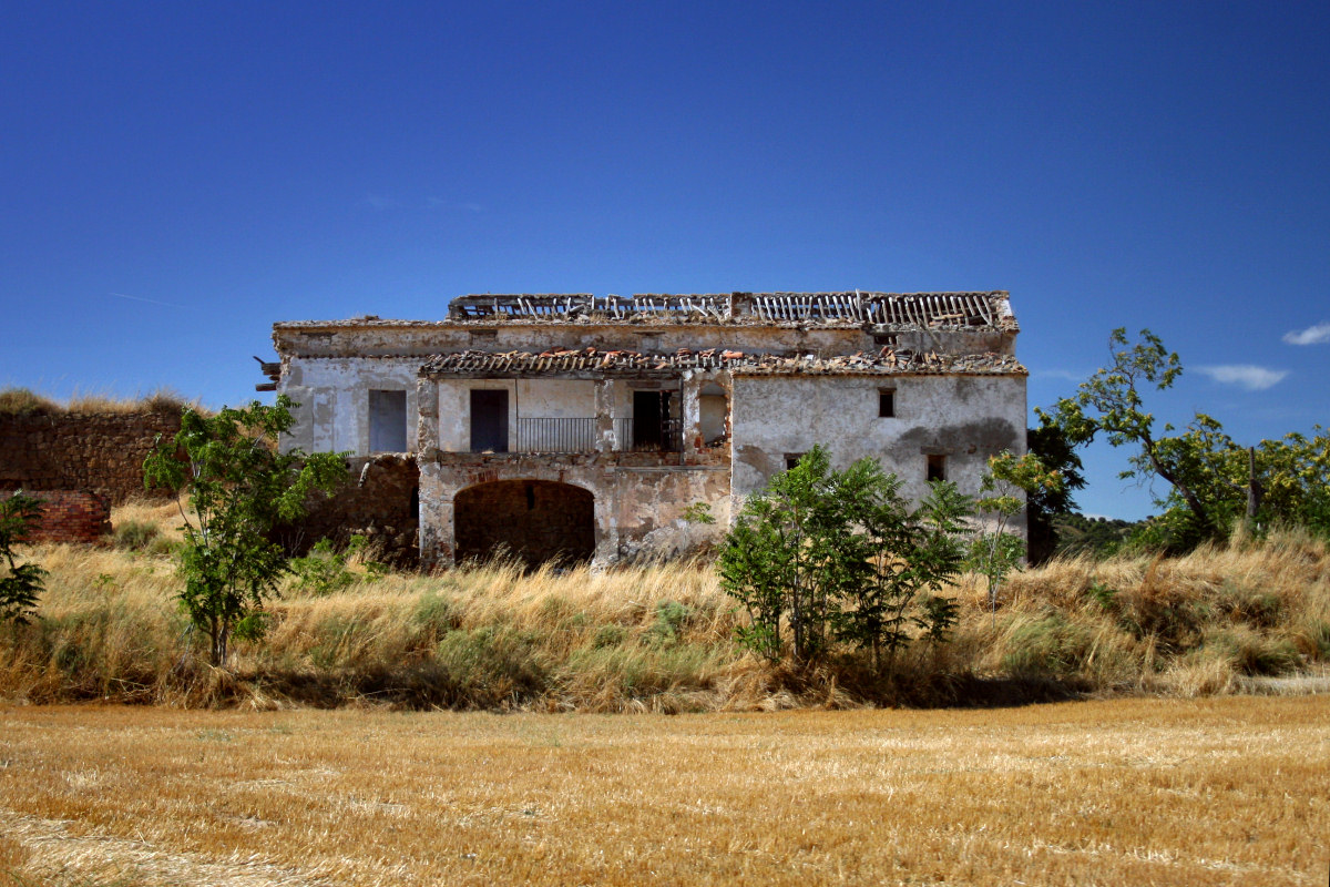 an old dilapidated house sits alone in a rural setting