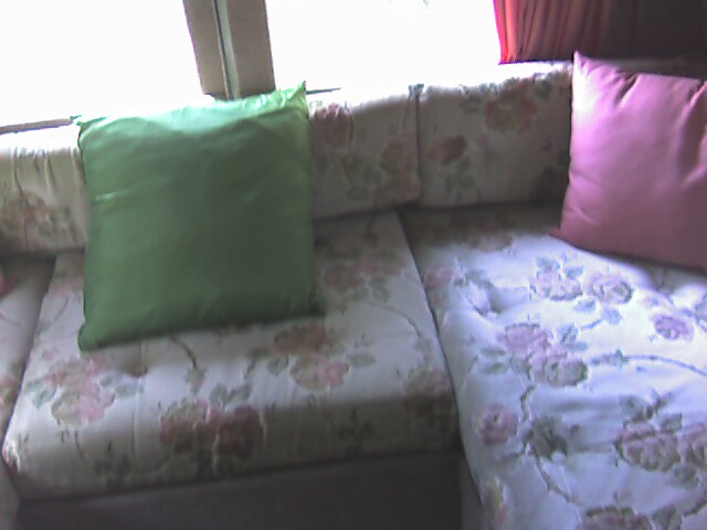 a colorful couch in front of a window with pink and green pillows