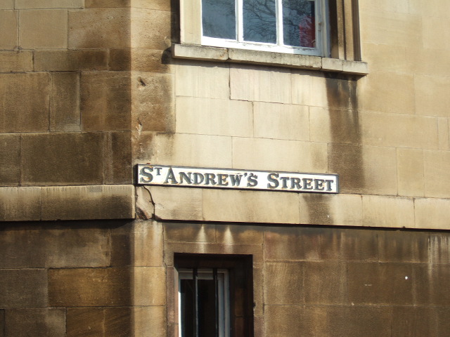 a building in the sunlight with a street sign