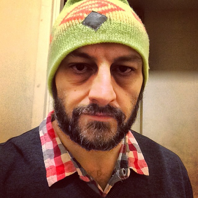 a man with a green knit hat looks into the camera