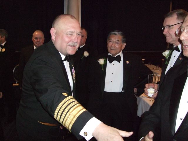 four older men in suit and tie shaking hands