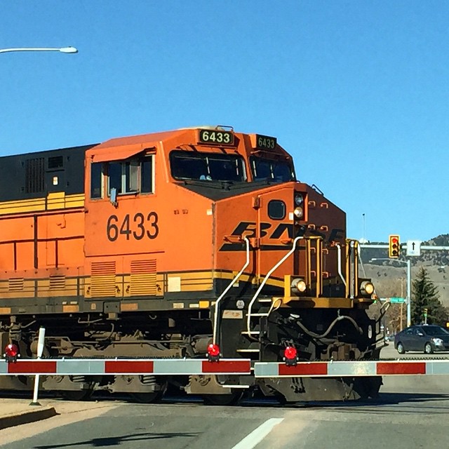 an orange train on a track in the middle of the street