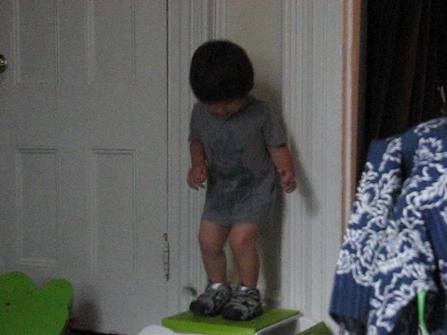 the little boy stands on top of a green floor mat