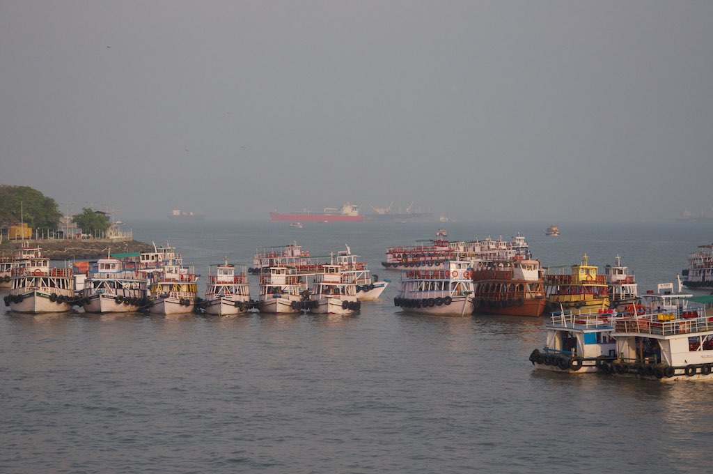 many boats are parked on the water with a big boat in the distance