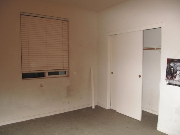 an empty room with an open door on one side and window on the other