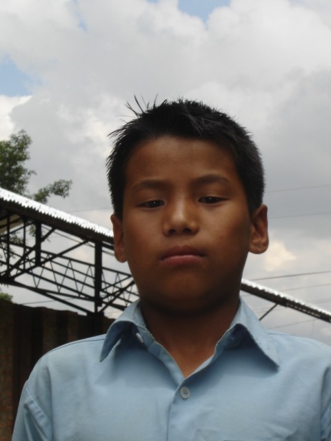 a boy wearing a blue shirt with no collar posing for the camera