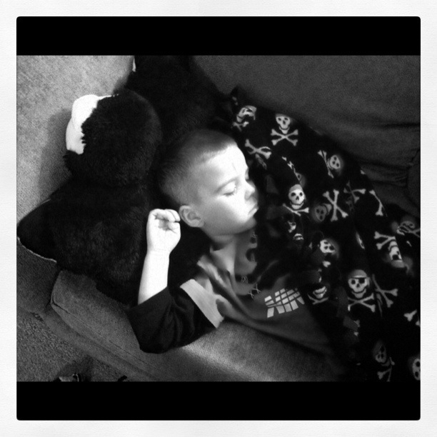 a child snuggling with a stuffed bear and laying on a couch