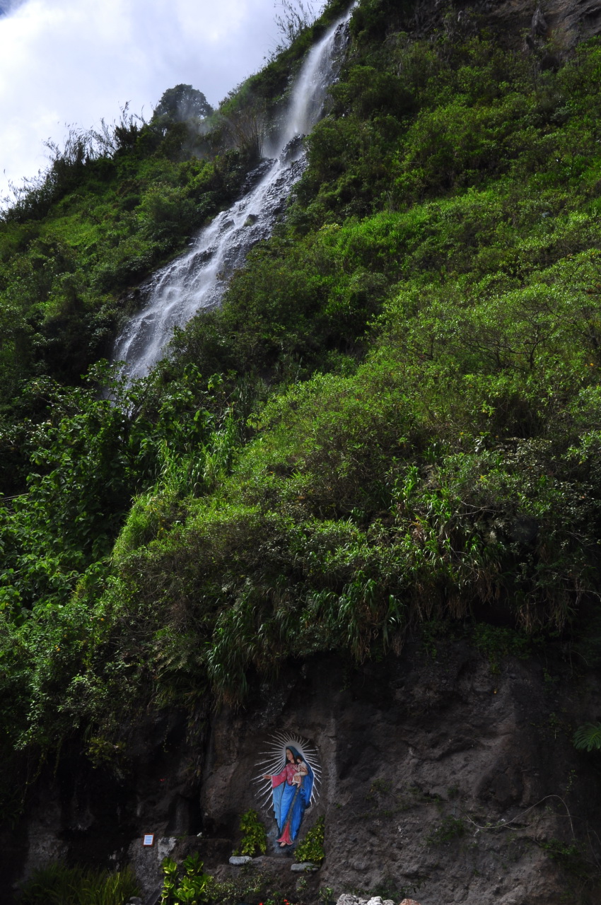 a man sitting under a small waterfall while wearing an umbrella