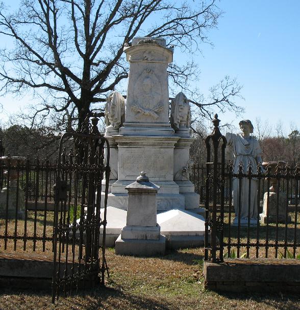 the cemetery has an old statue and black iron fence