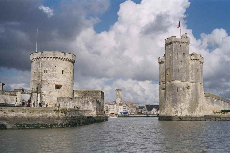 two large towers on the water by some buildings