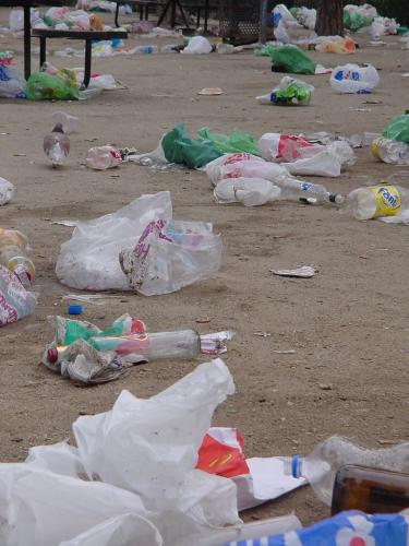 trash strewn around and near trash containers on the ground