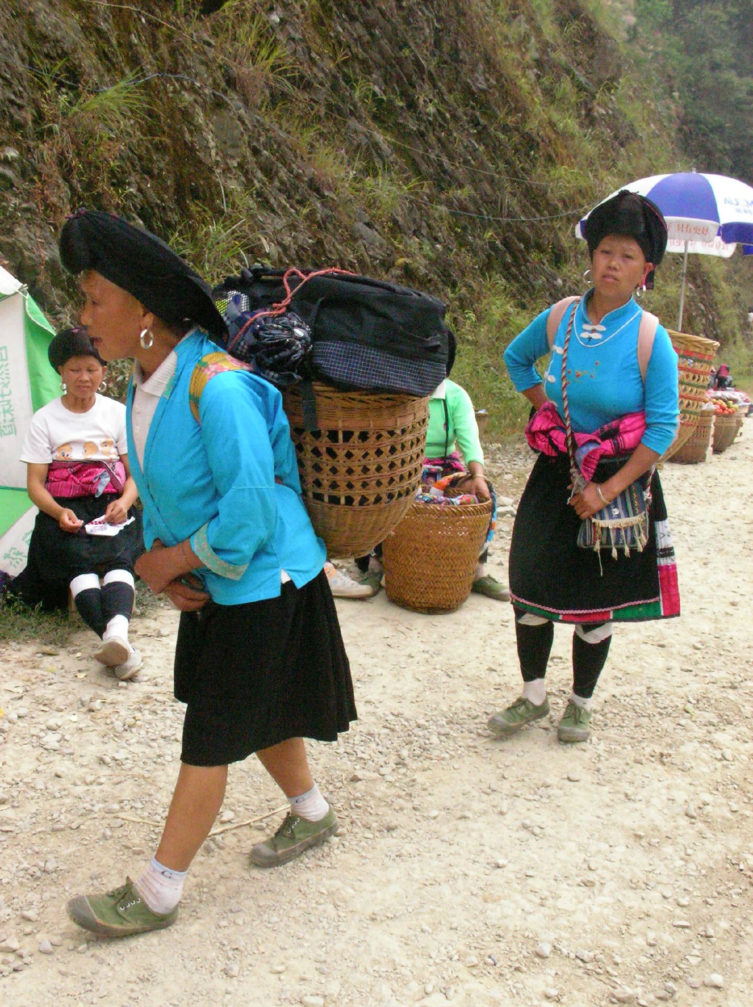 women in traditional mexican clothing walking down the dirt road
