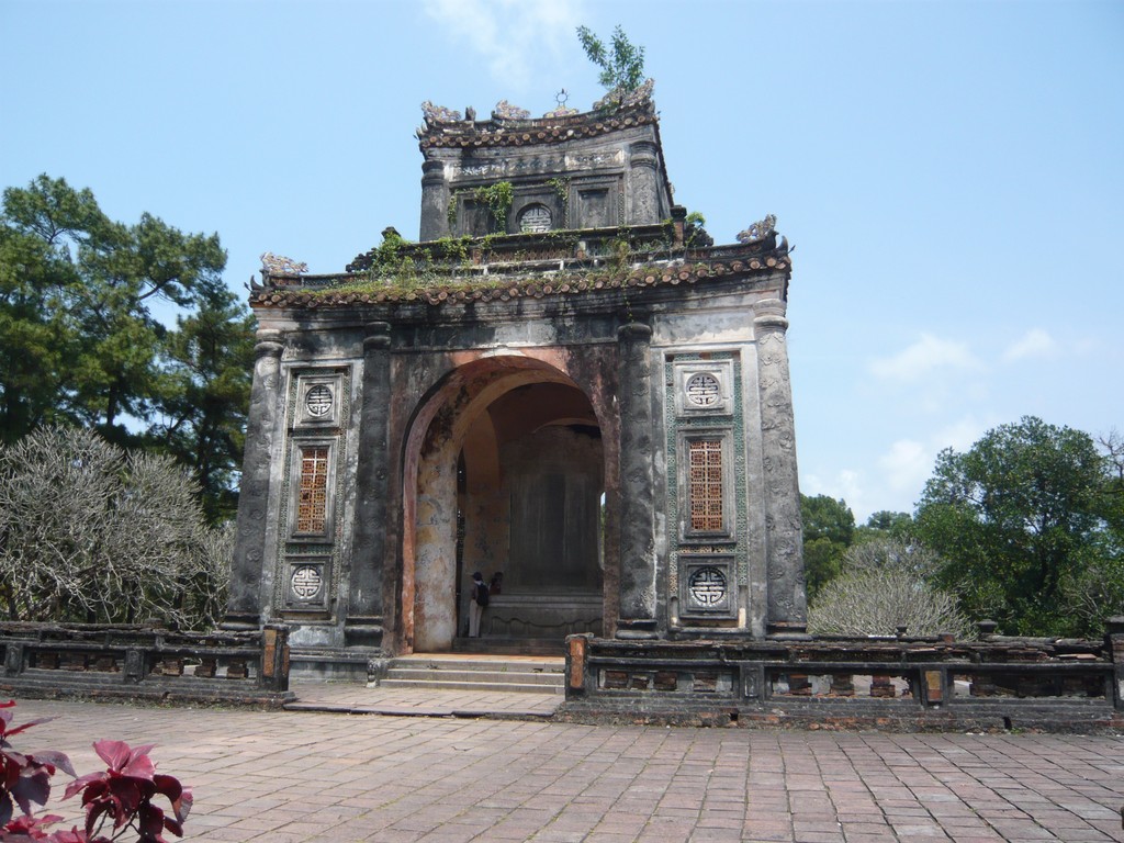 an ancient stone building has vines growing over the door