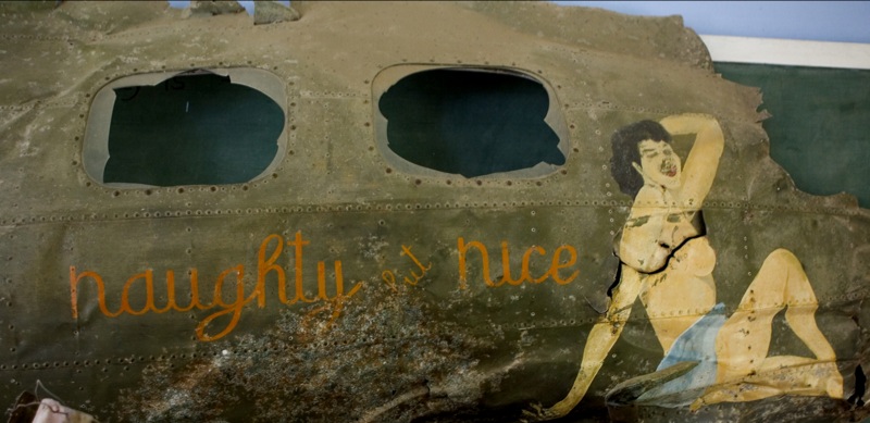 an old plane with holes and a woman painted on the side