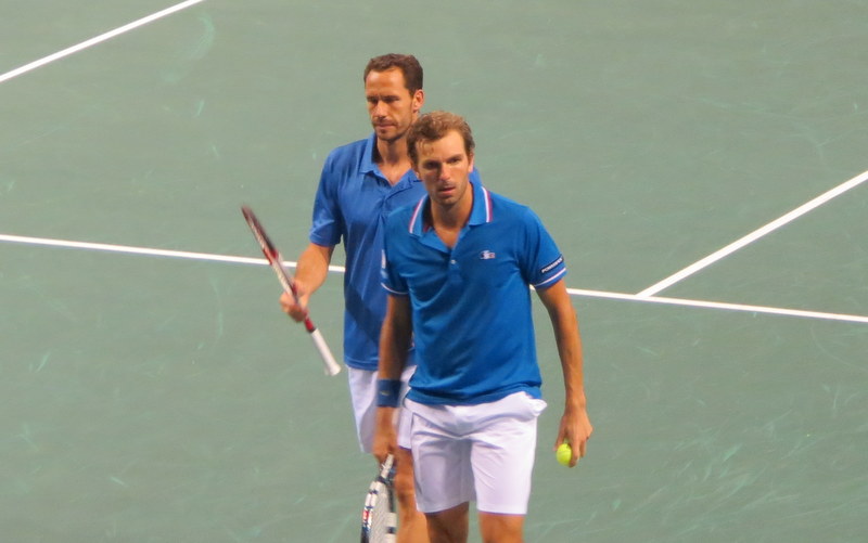 two men standing on a tennis court holding tennis rackets