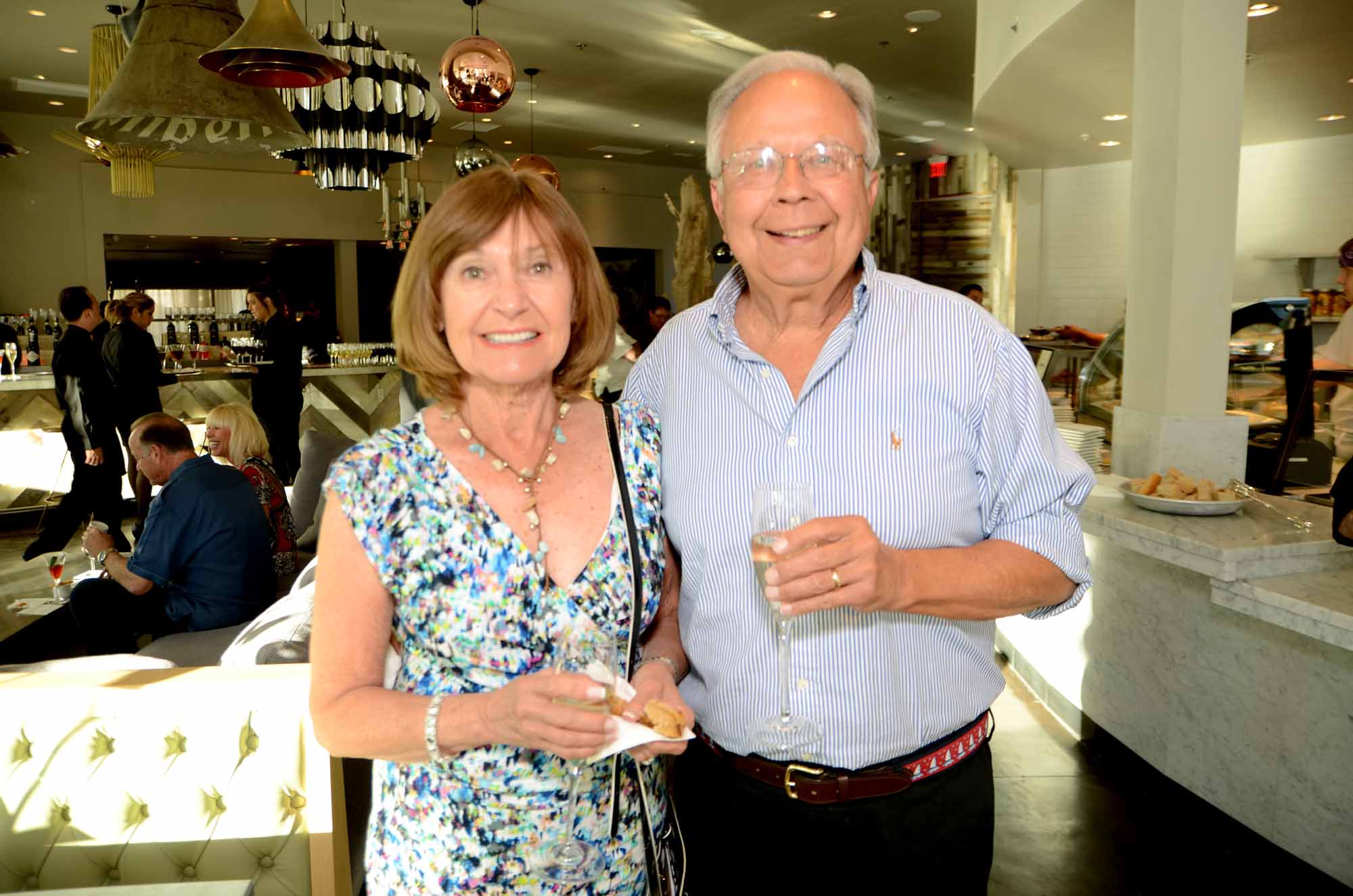 an older couple standing in a restaurant holding onto some food
