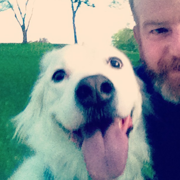 a man standing next to his dog and smiling