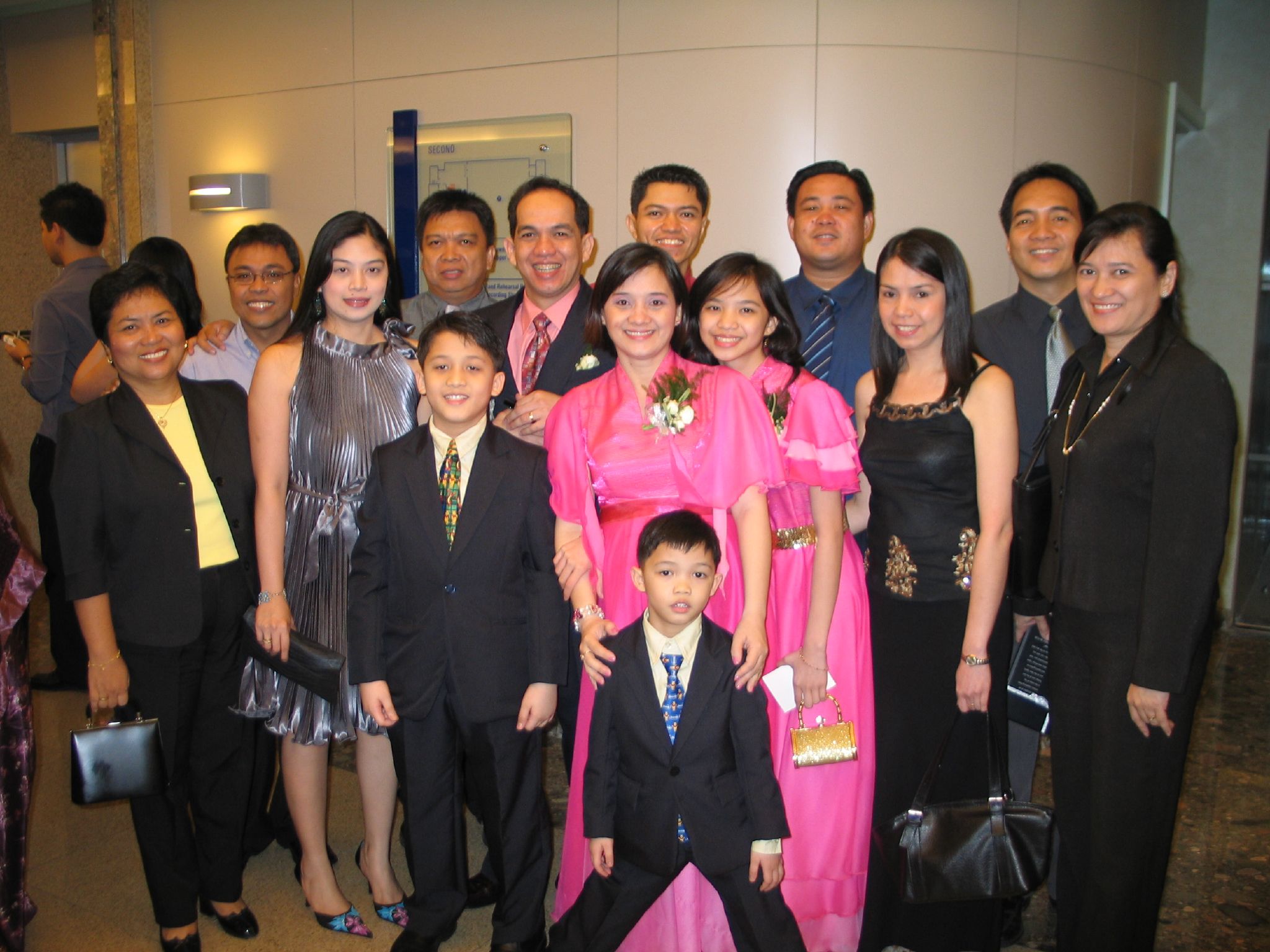 an adult standing with a child between two adults, two children and a man in a suit and tie