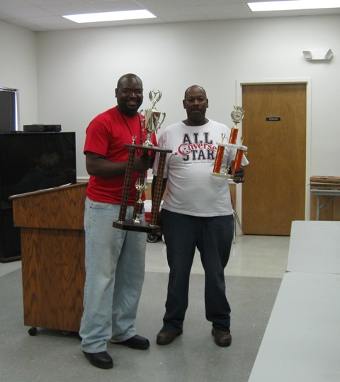 two men holding trophy trophies standing next to a podium