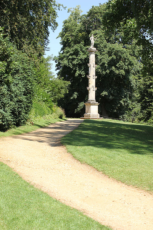 the dirt path leads to an obelisk in a park