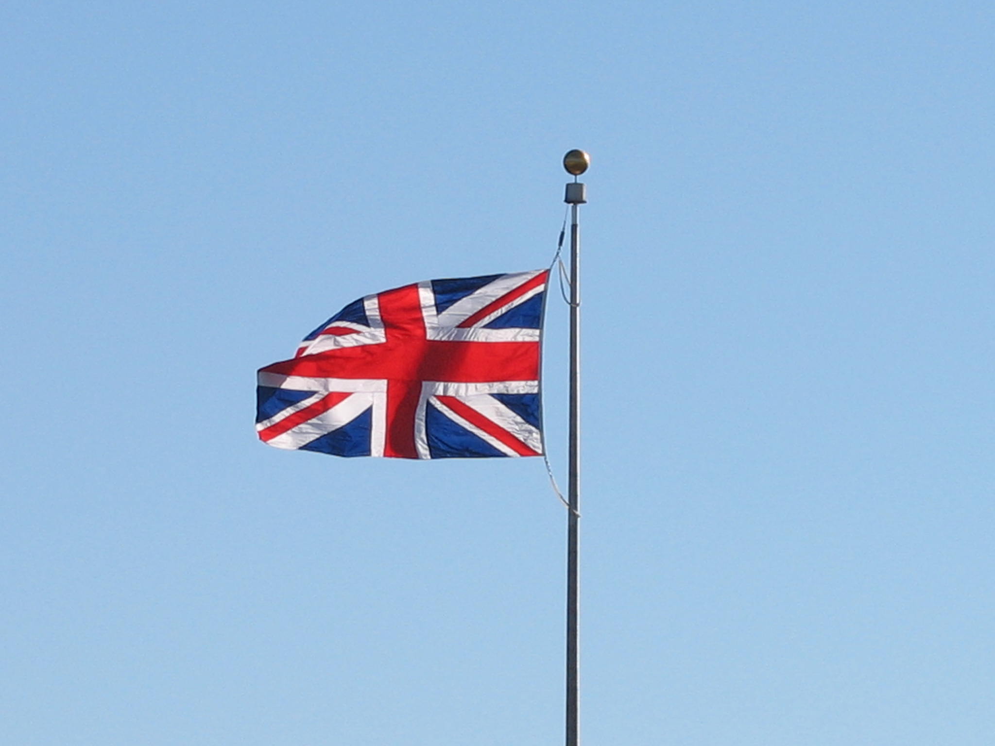 a flag flying in the wind next to a street light