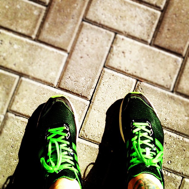 person's feet with green and black shoes