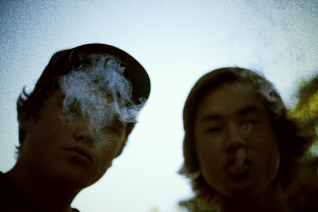 two young men standing and smoking cigarettes