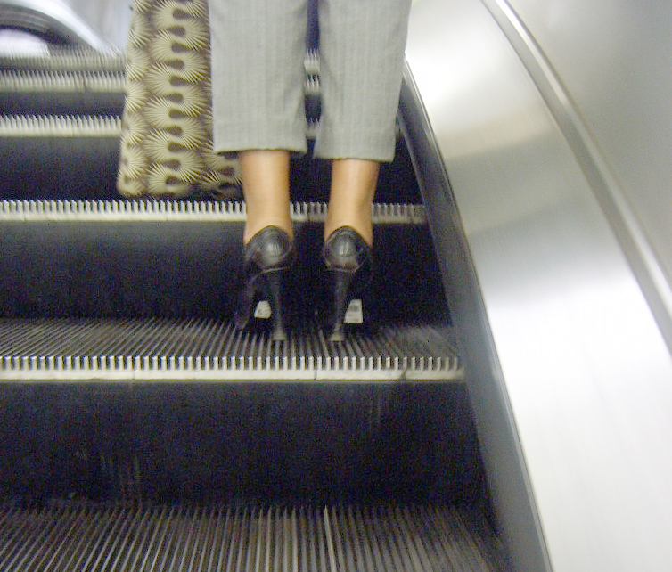 a woman walking up an escalator in high heels