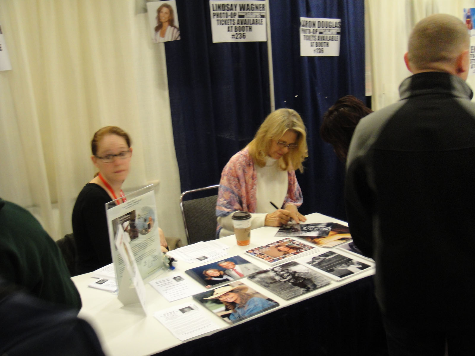 a woman at a table signing papers and drinking a cup of coffee