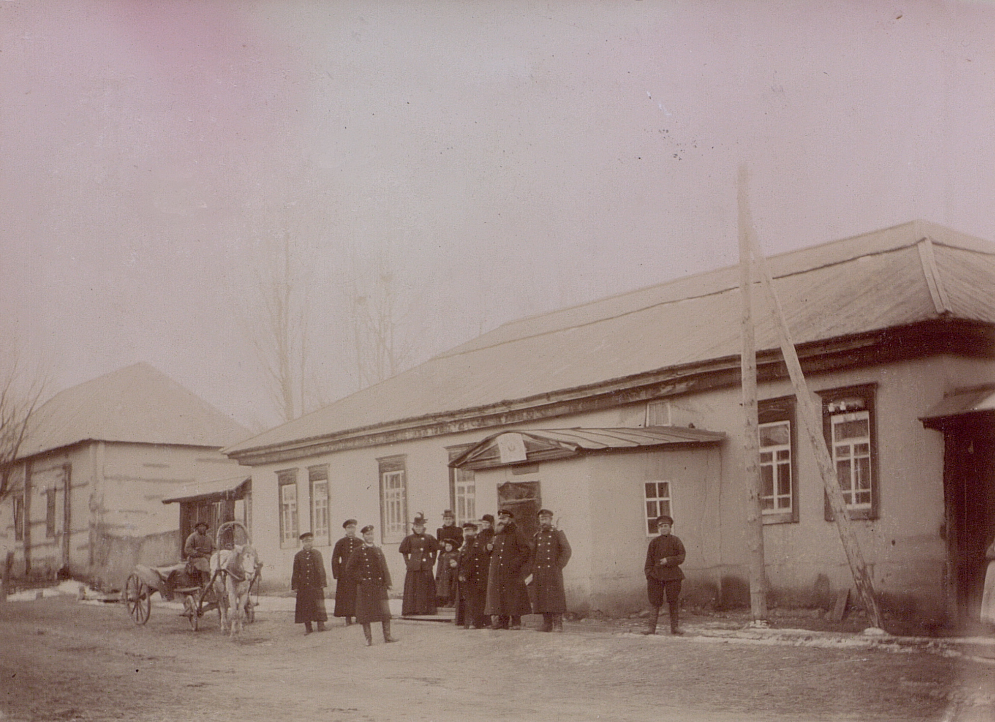 several men standing outside of a building with horses and carriages