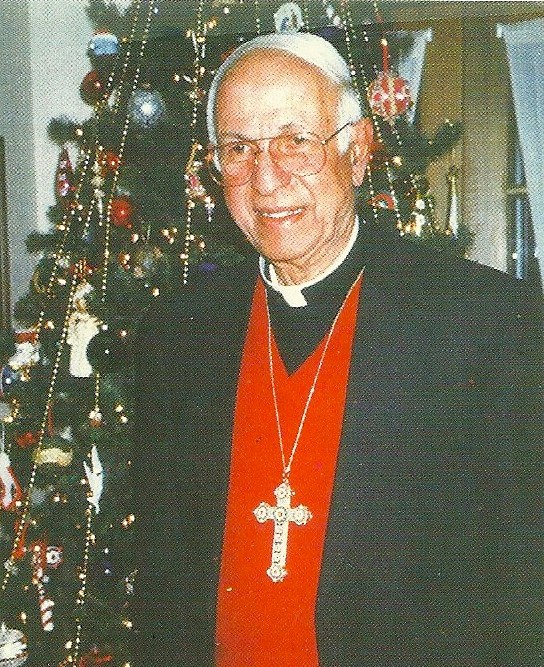 an older man is wearing a red outfit and a white and black cross on his neck