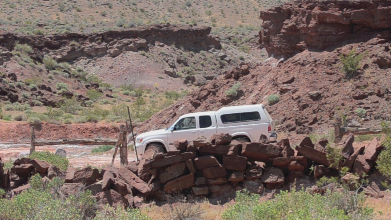 a van parked next to the rocks on the side of a hill