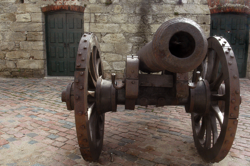 a large old rusty metal cannon on a brick ground