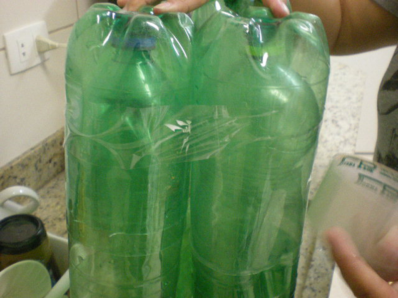 a close up of two people holding up bottles filled with green plastic