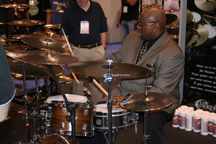 a man with glasses on playing drums in front of people