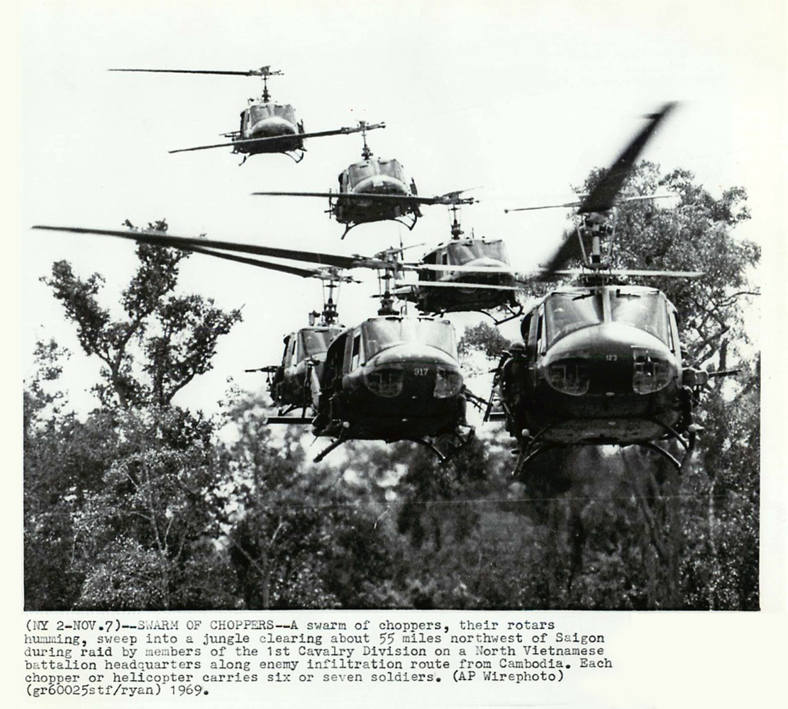 a group of four military helicopter flying over trees