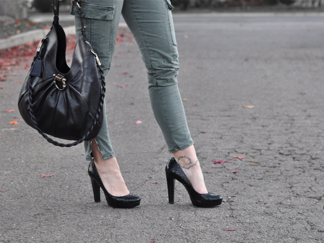 a lady in green jeans and black shoes walking in the street