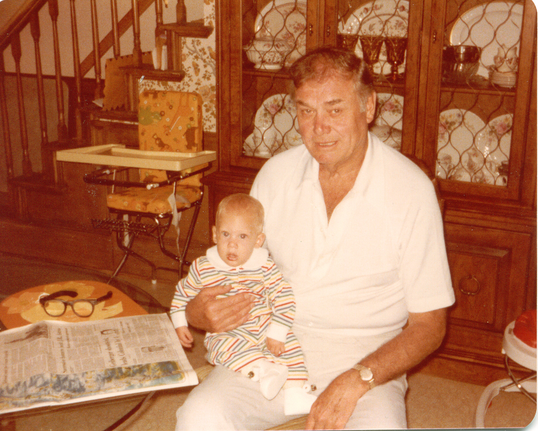 an older gentleman is holding a toddler who is looking at the camera